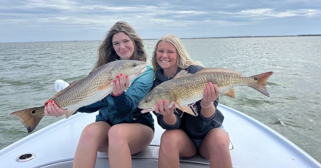Two anglers holding redfish trophy catch on a fishing boat