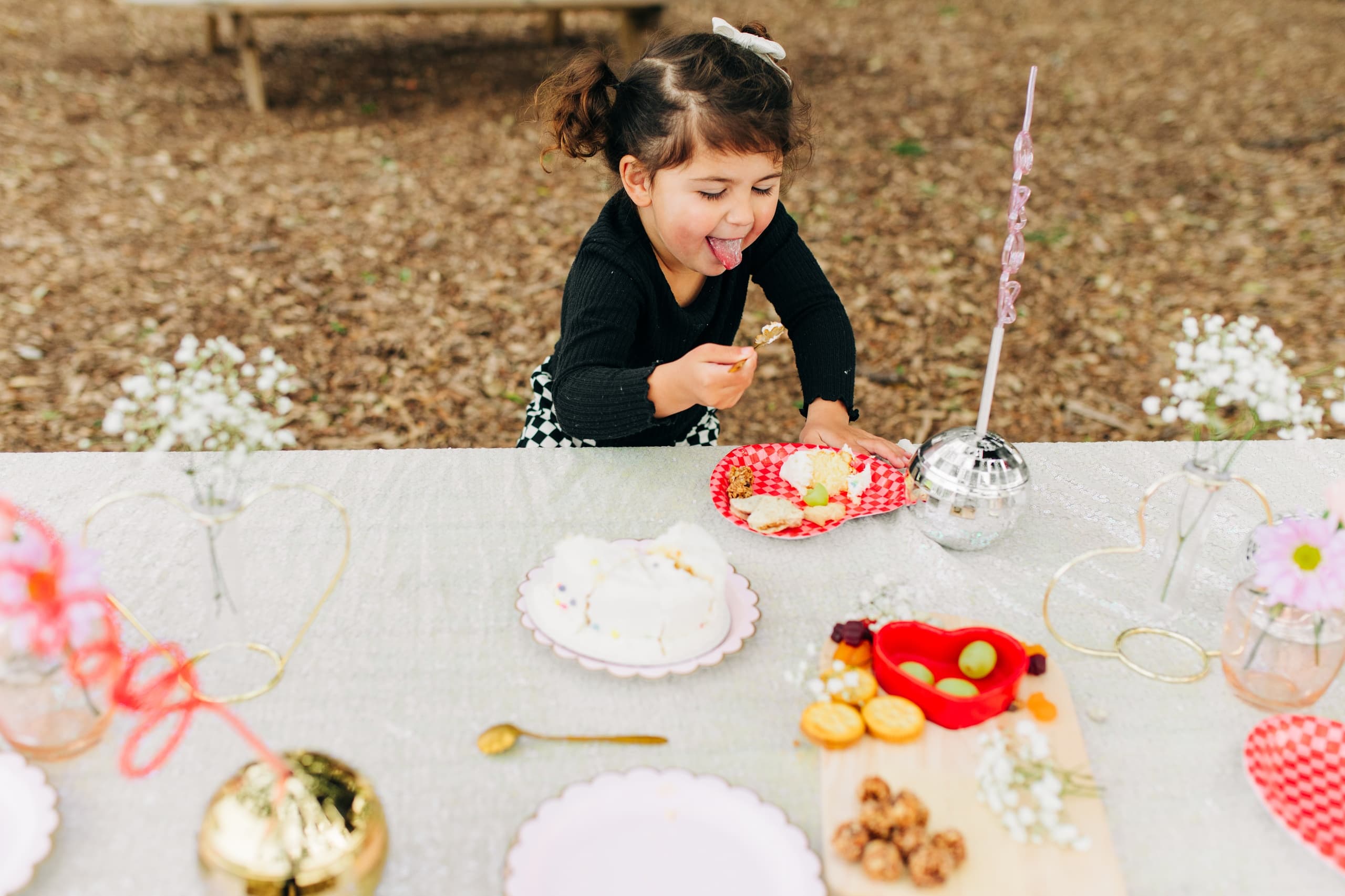 Child enjoying picnic treats at decorated outdoor party table