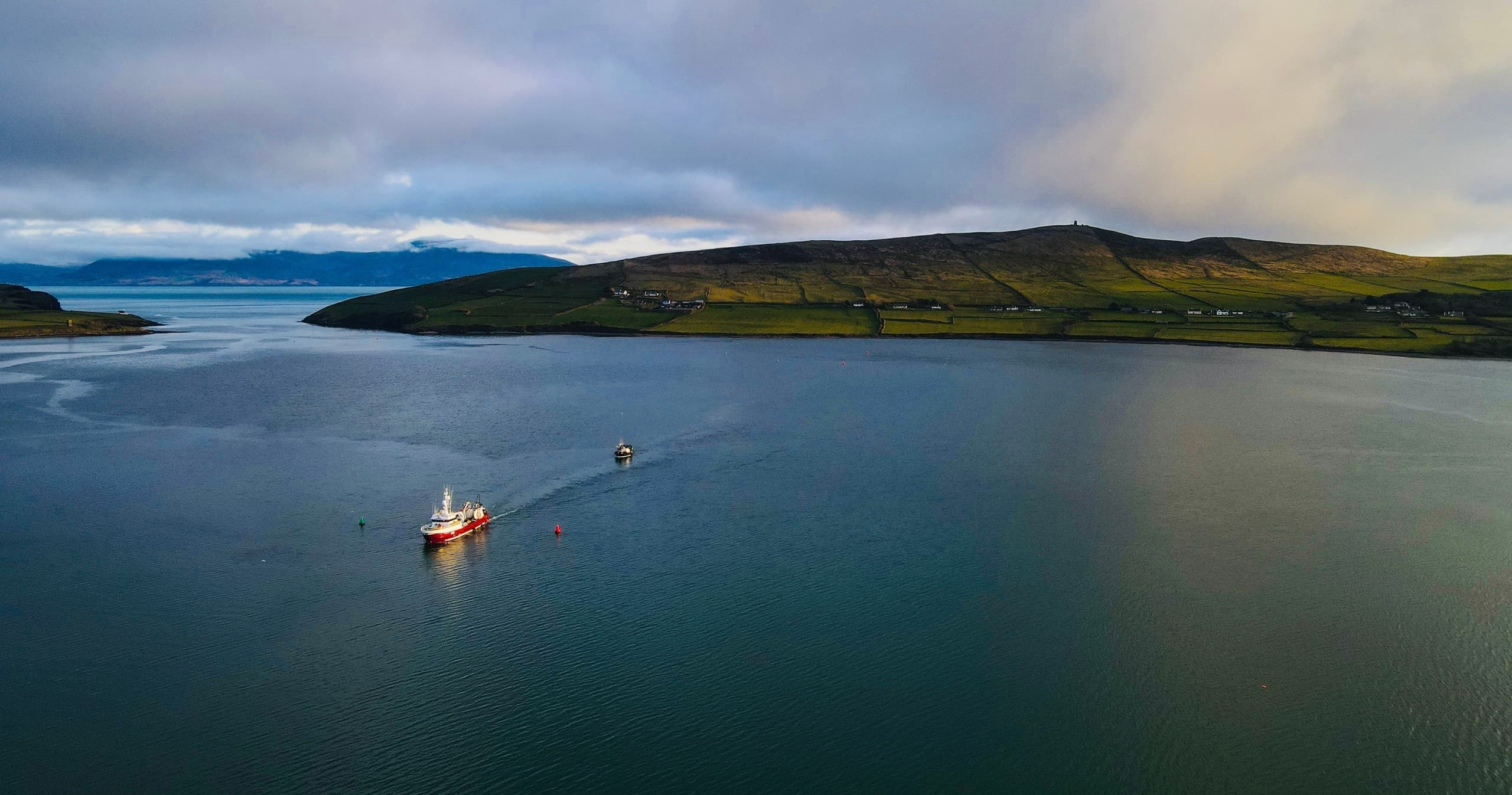 Aerial view of fishing boat on calm bay near Dingle coastline