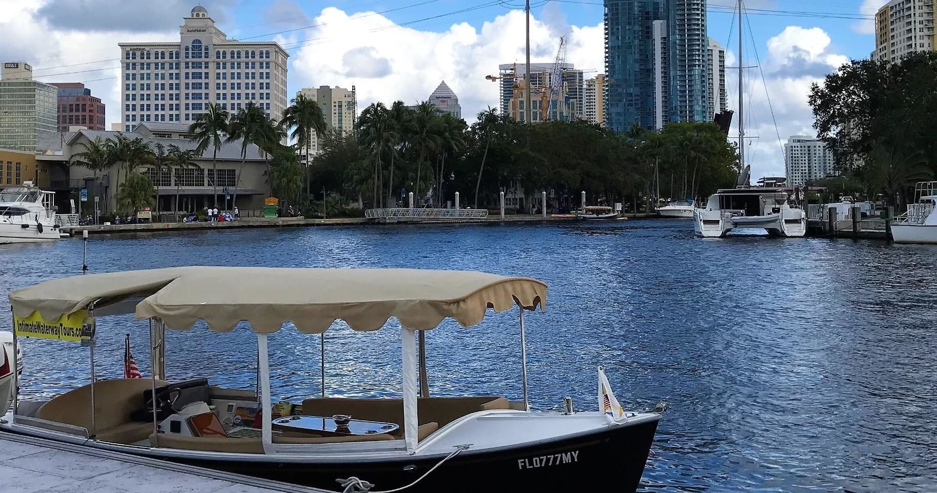 Covered sightseeing boat cruising urban waterway with city skyline