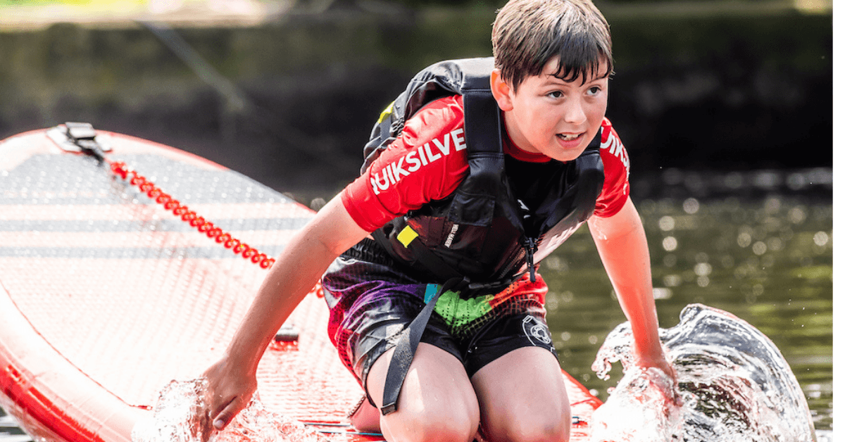 Child paddling on a paddleboard, splashing on sunny river session