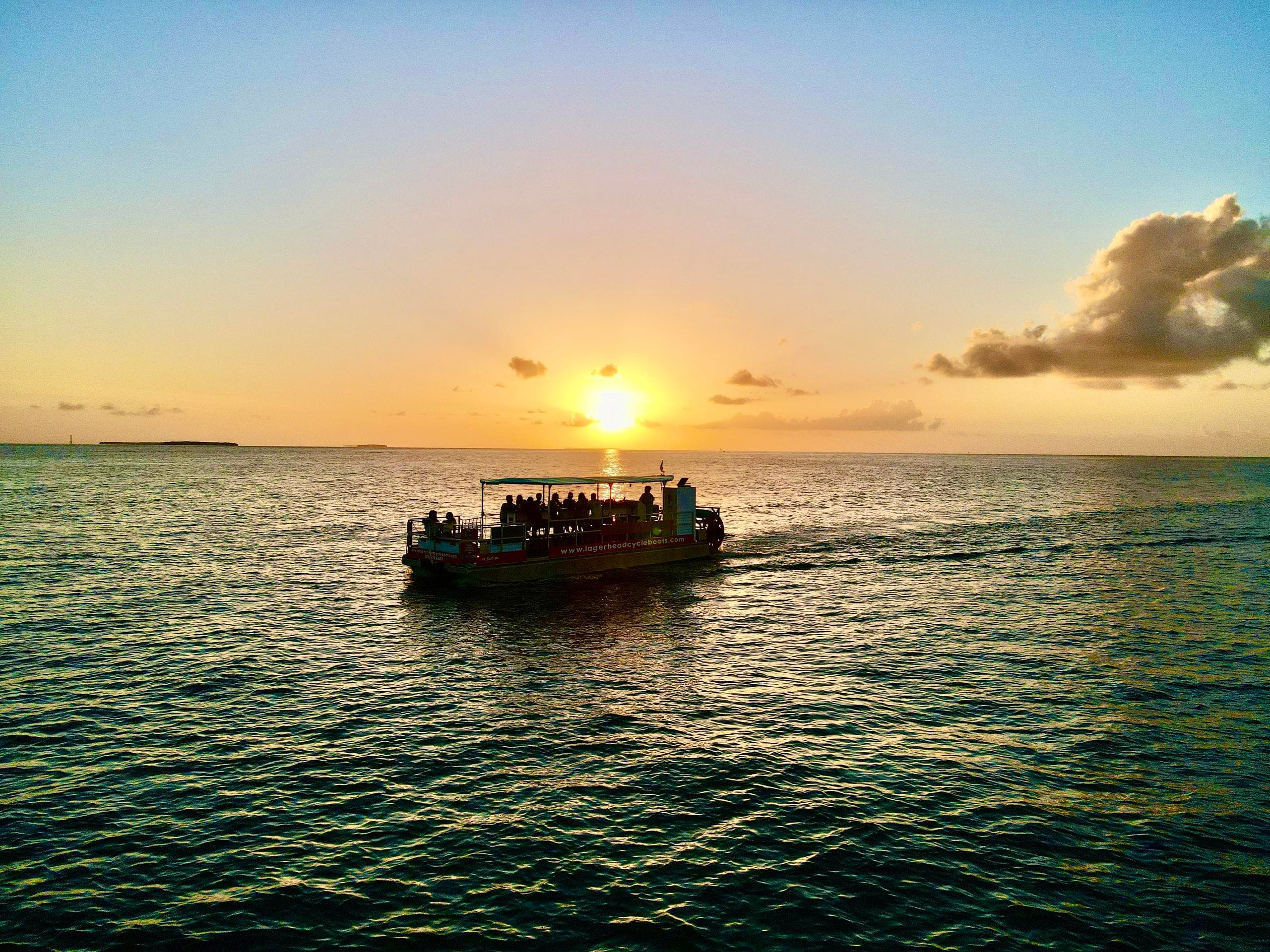 Small sightseeing boat at sunset over turquoise Key West waters