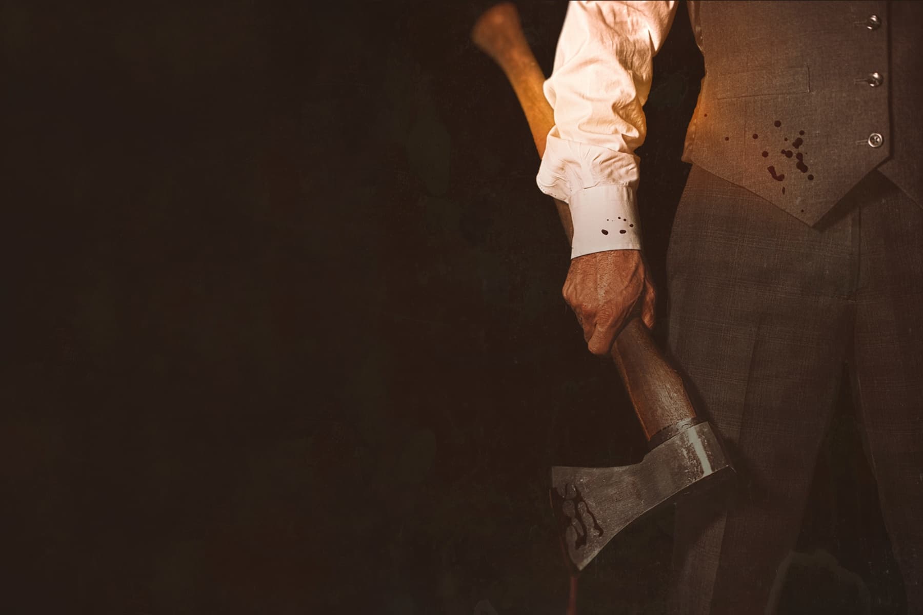 Close-up of man gripping axe in dim workshop, ominous mood