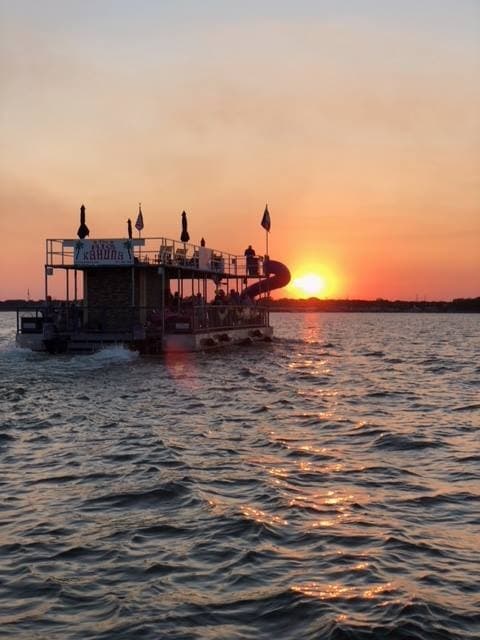 Sunset boat cruise on lake with calm water and silhouetted deck