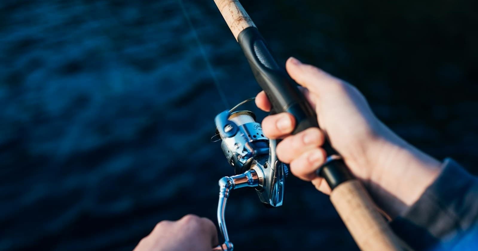 Angler reeling fish from boat over deep blue water at sea