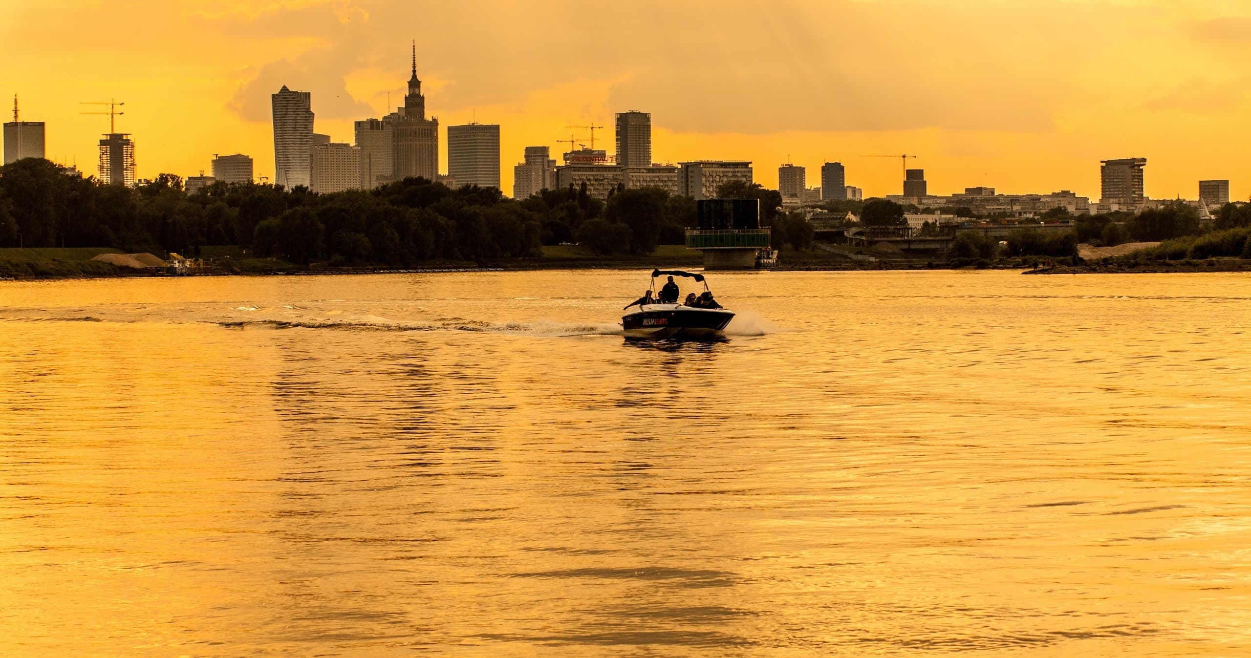 Golden-hour boat cruising near city skyline on calm river