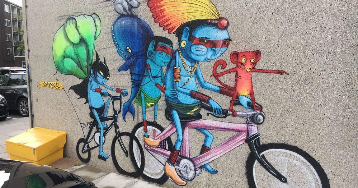 Colorful street mural of cyclists on urban Amsterdam building wall