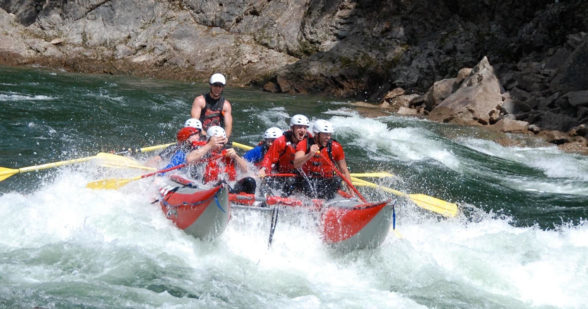 Multi-person raft charging through turbulent river rapids with guide