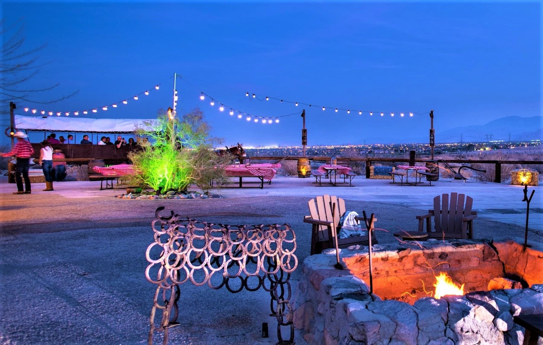 Lakeside evening campfire seating with string lights at dusk