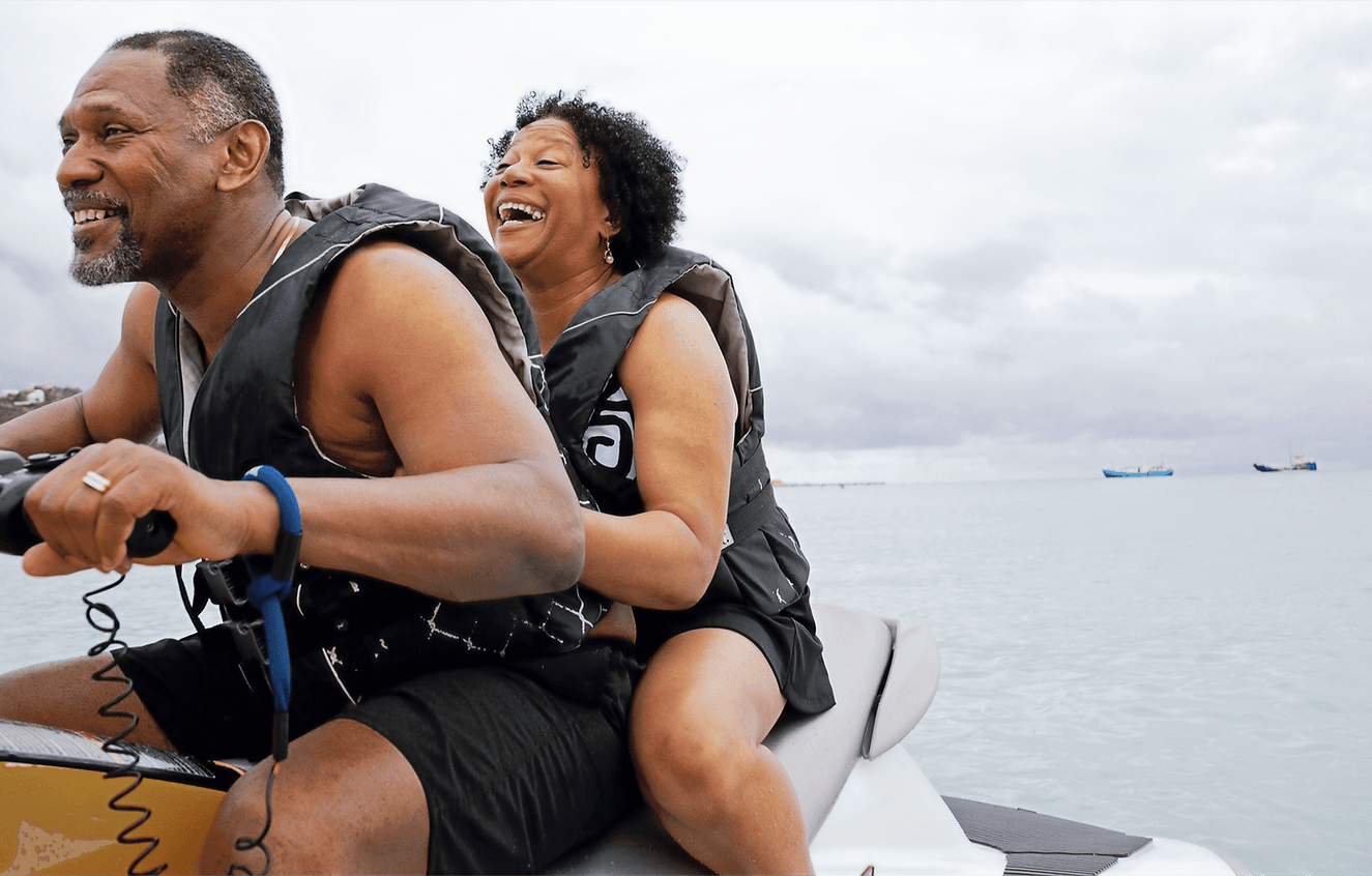Couple enjoying a jet ski ride smiling on calm coastal waters