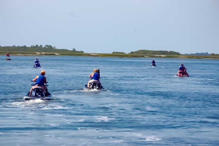 Group of jet ski riders cruising on open ocean waters near shore