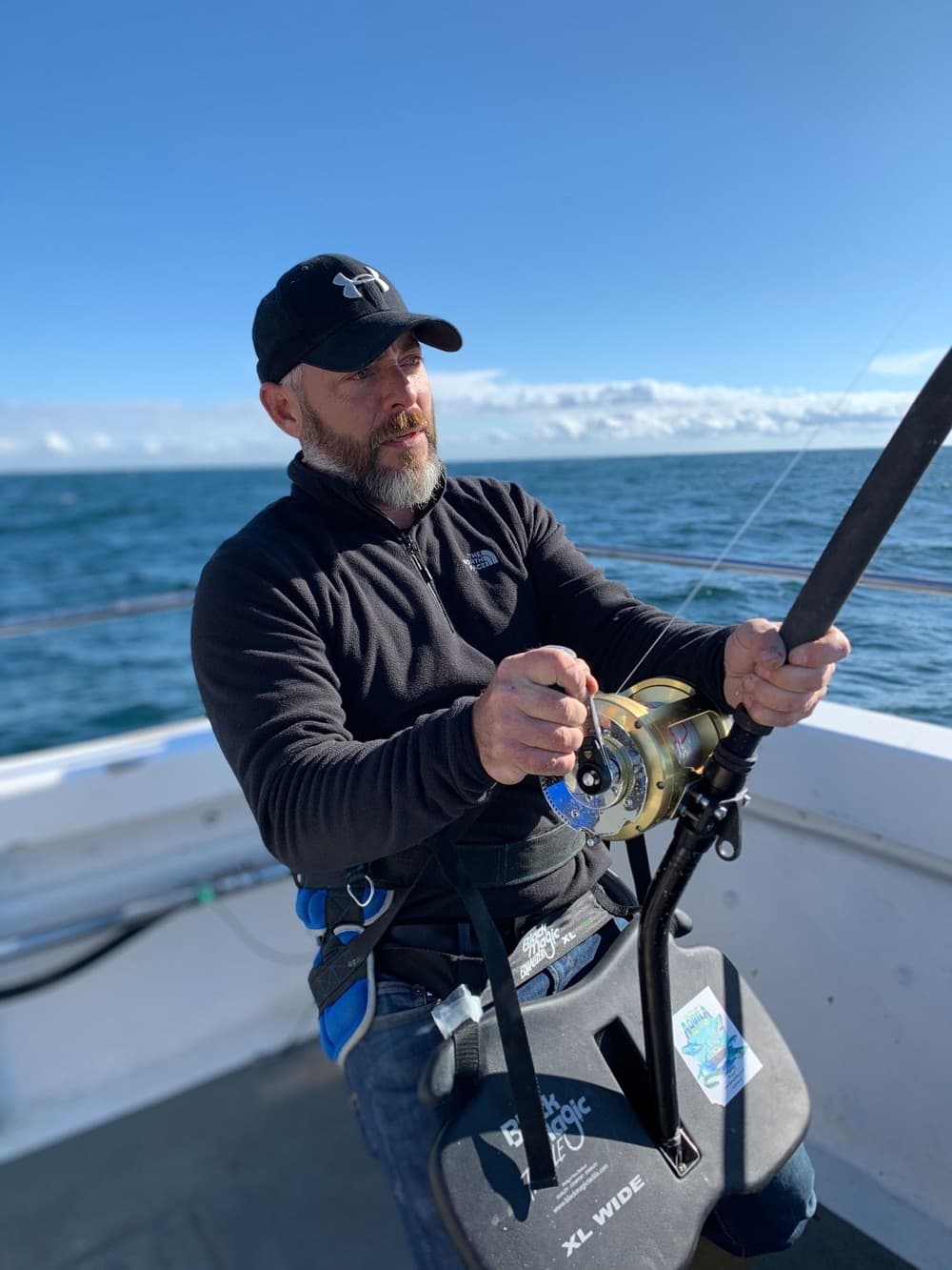 Focused angler fighting a deep-sea fish on offshore boat