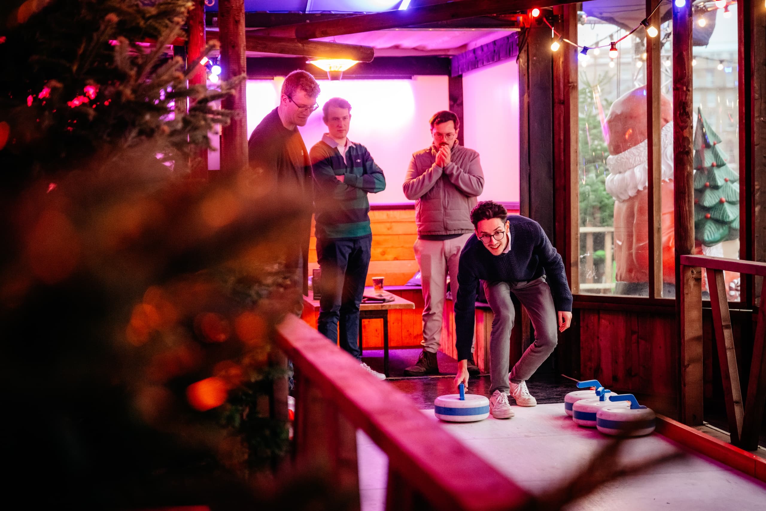 Group playing indoor shuffleboard in festive wooden Christmas stall