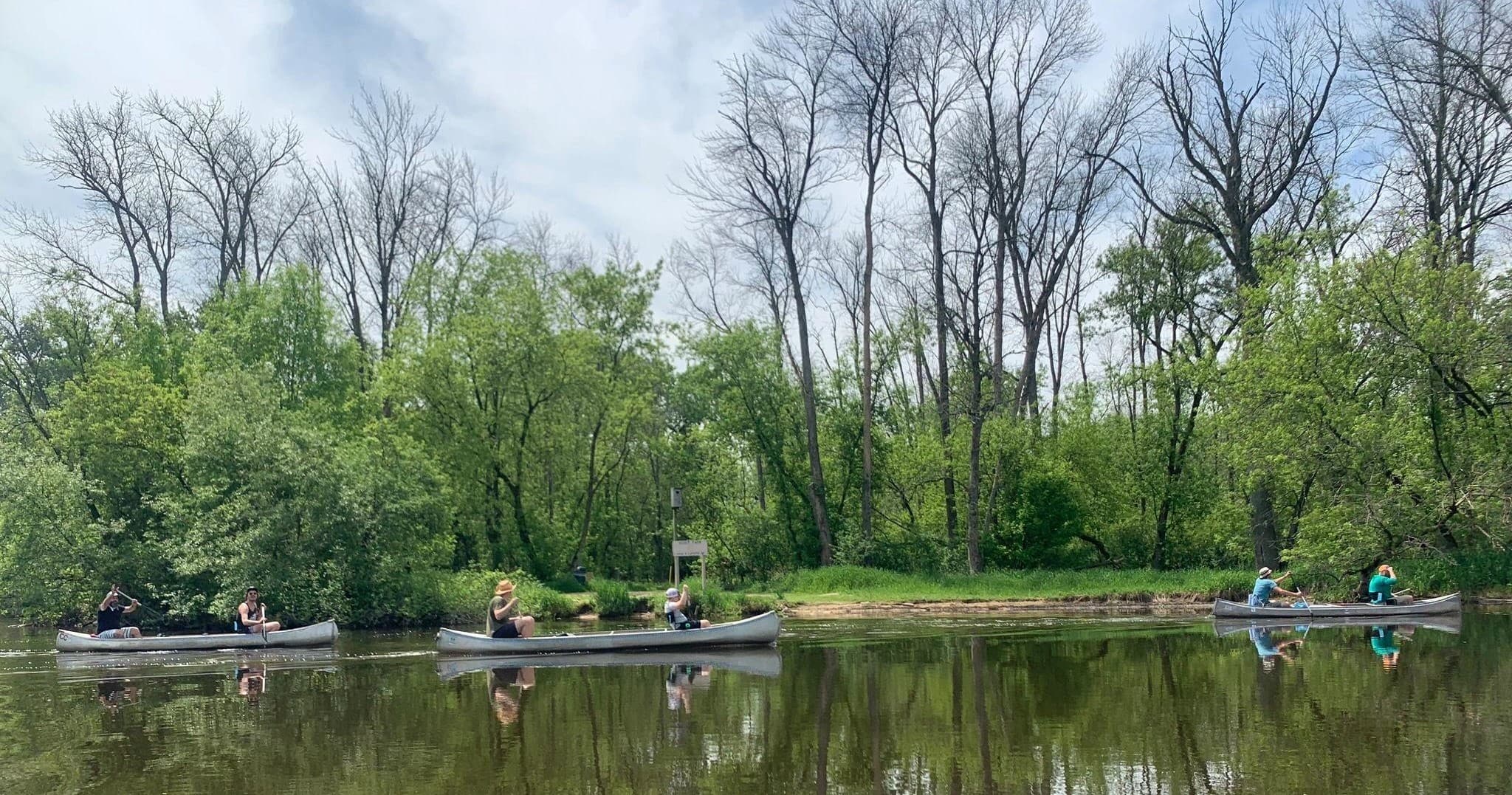Kayakers paddling on calm tree-lined river in spring