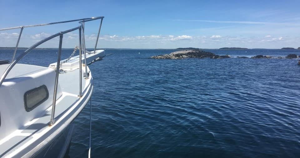 Boat bow cruising toward open coastal island waters at sea
