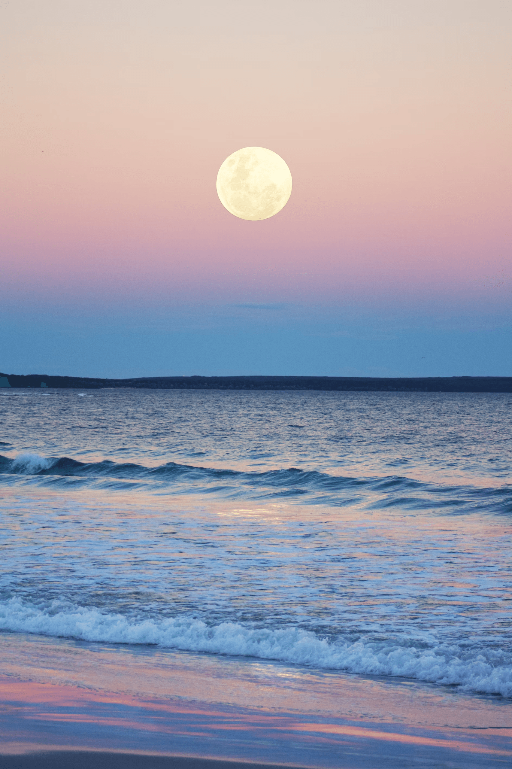 Full moon rising over pastel ocean horizon with gentle waves