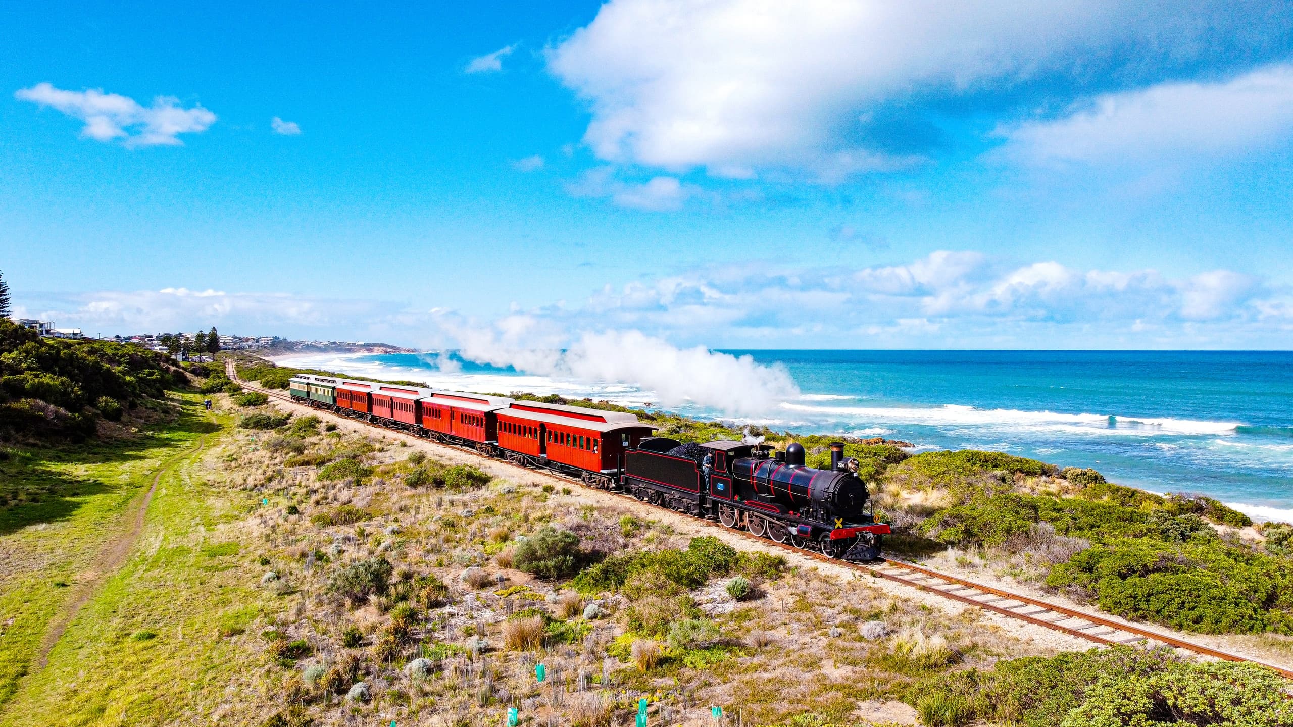 Vintage steam train traveling along coastal dunes with ocean views