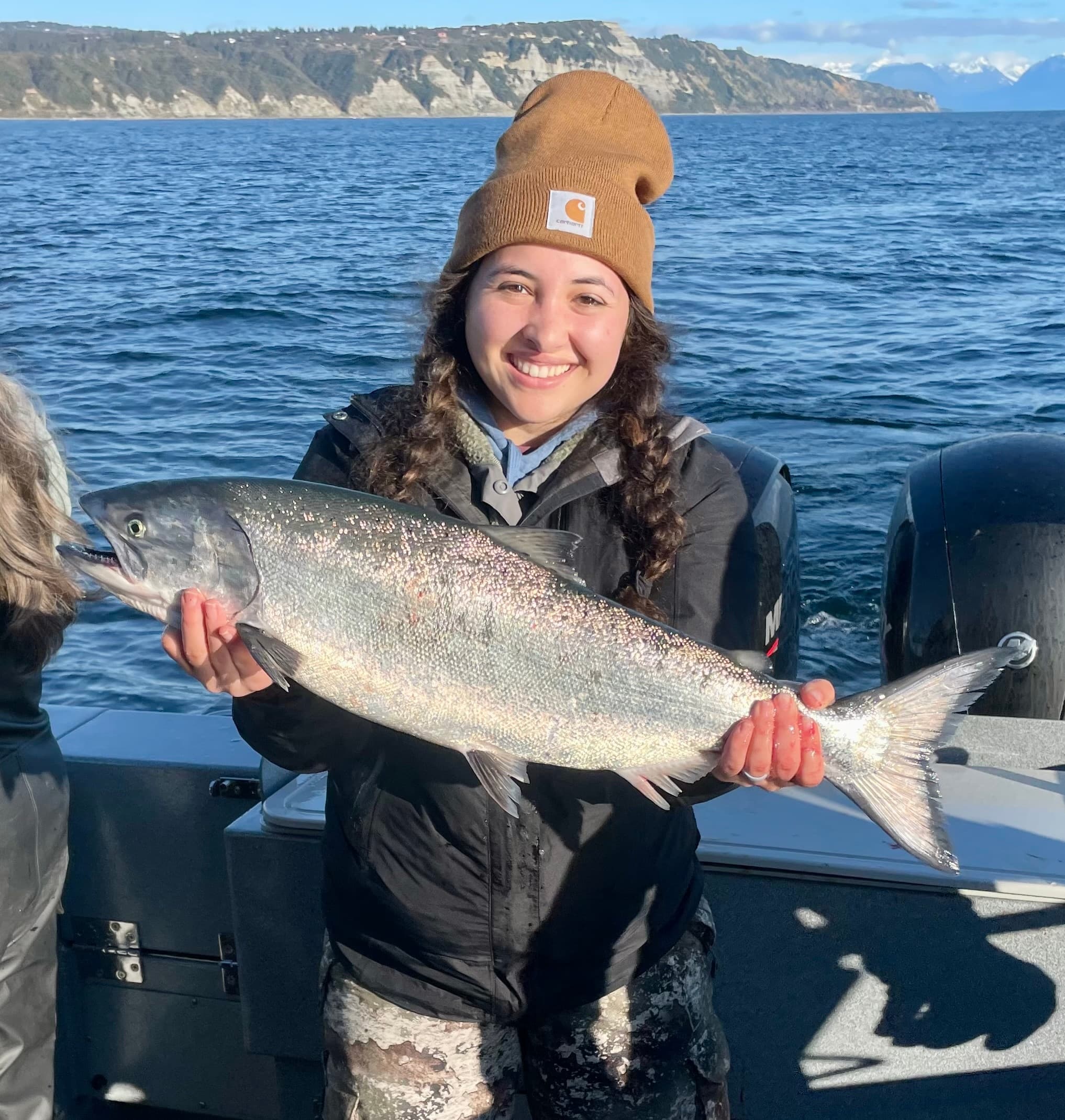 Angler holding large salmon with coastal cliffs and ocean view