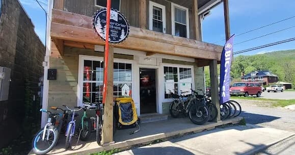 Small town bike shop porch displaying e-bikes and rentals by road