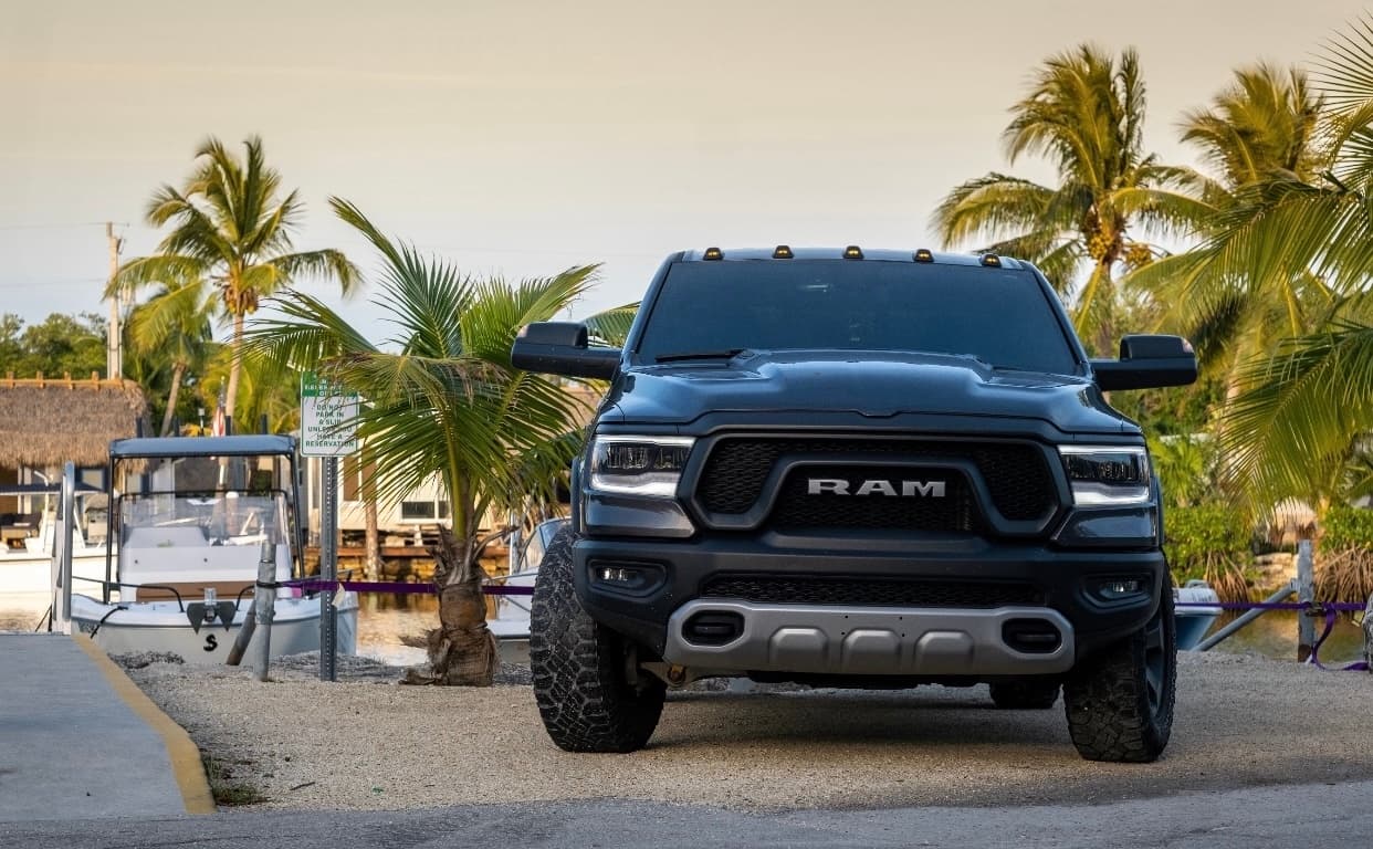RAM pickup parked on beachfront with palm trees, coastal off-road