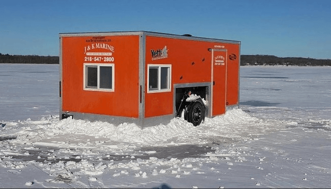 Orange ice fishing house on frozen lake for winter angling