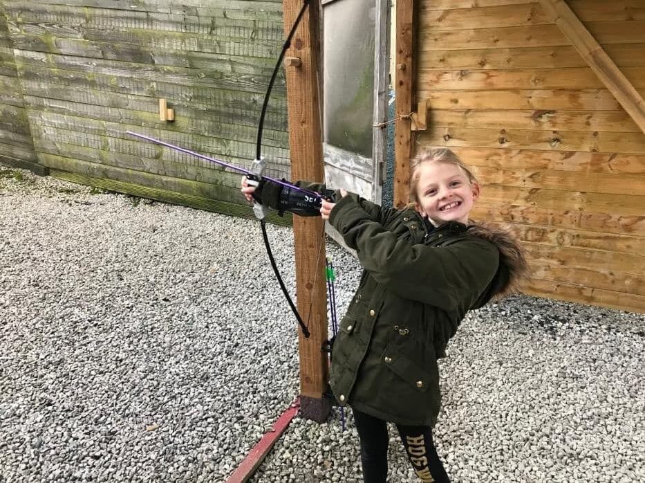 Child practicing outdoor archery on gravel range at activity center