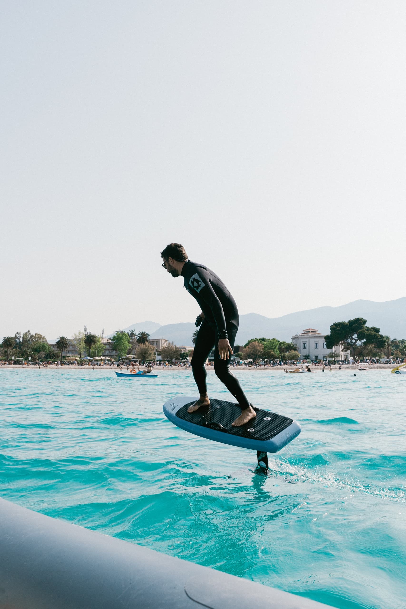 E-foil surfer gliding over turquoise coastal waters near beach