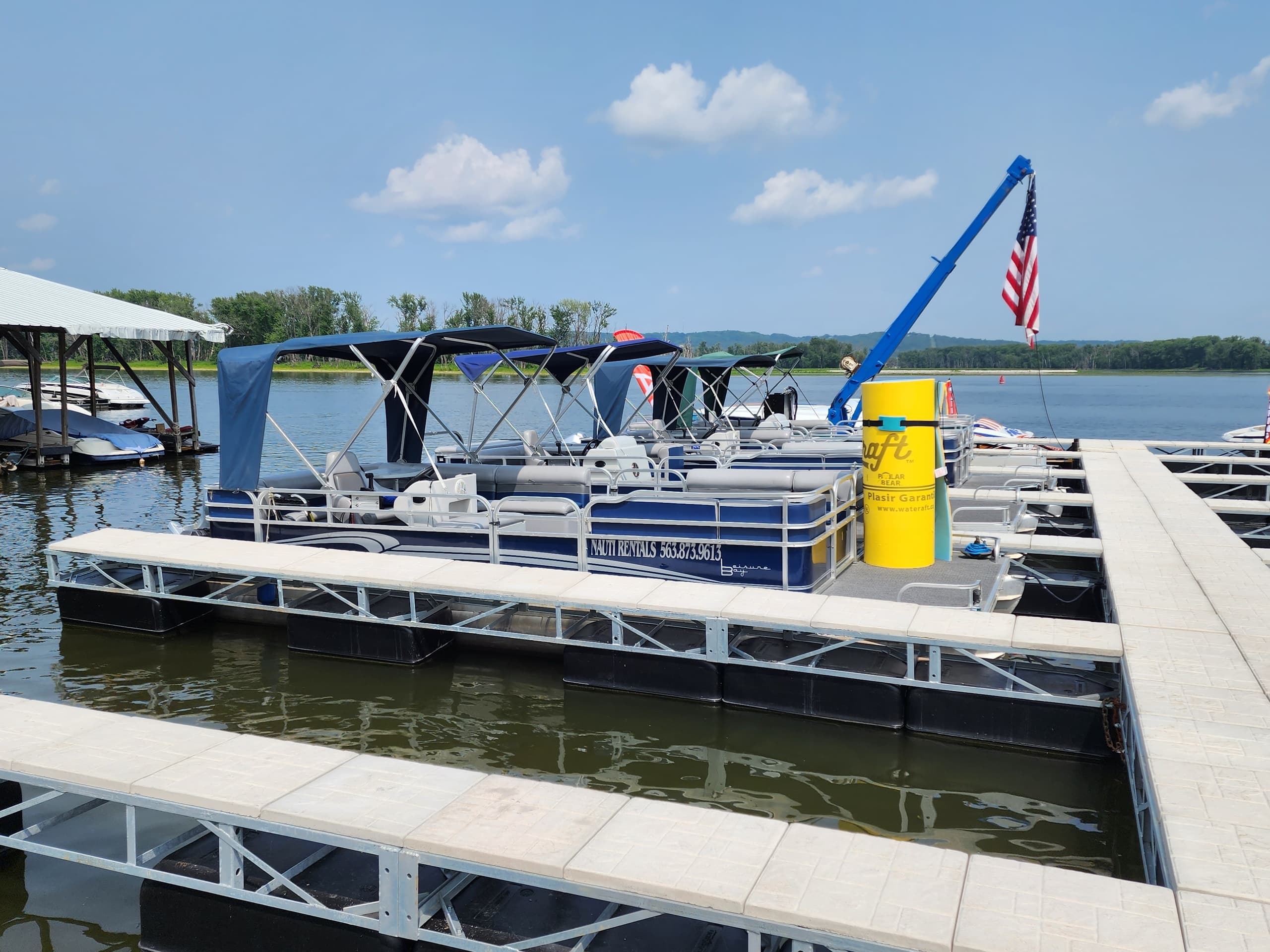 Pontoon boat docked at marina with American flag, lake outing