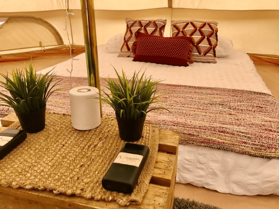 Styled glamping tent bedside table with plants and soft bedding