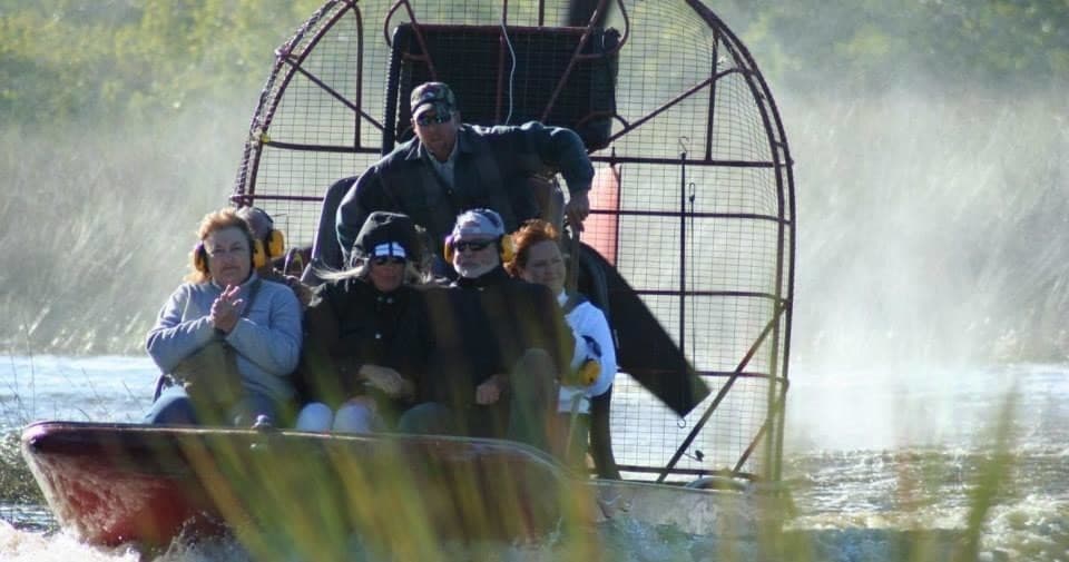 Airboat speeding through Everglades grass with tourists