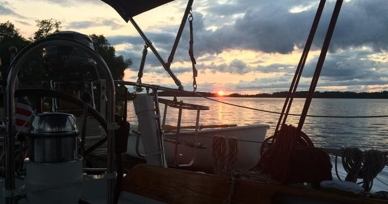 Sunset view from sailboat cockpit overlooking calm harbor waters