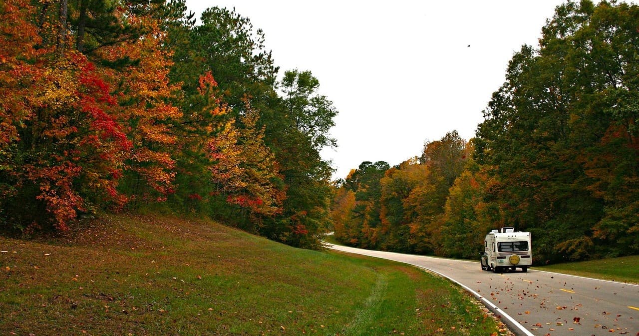 RV driving on scenic autumn road through forested hills
