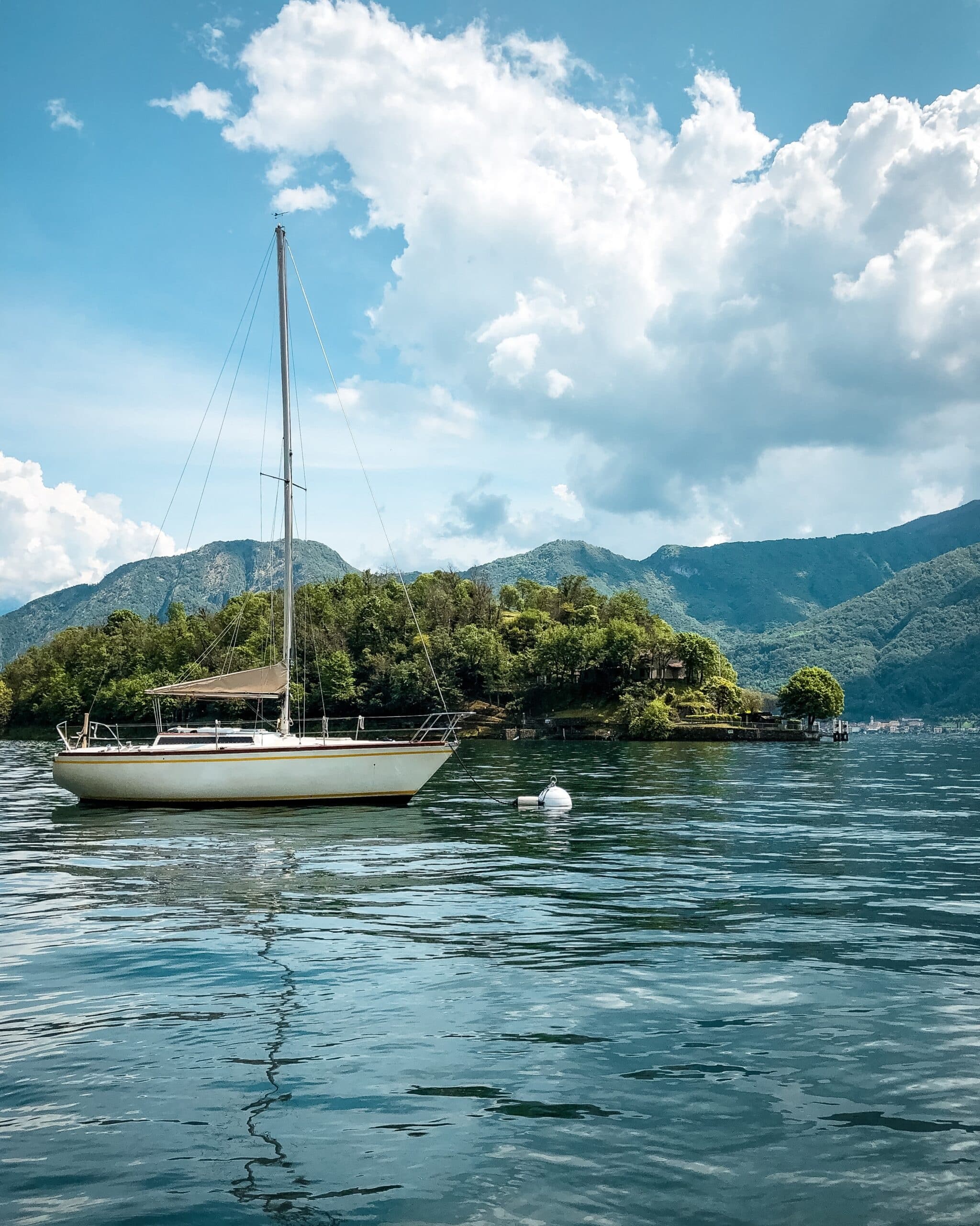 Sailboat anchored on calm mountain lake under blue sky