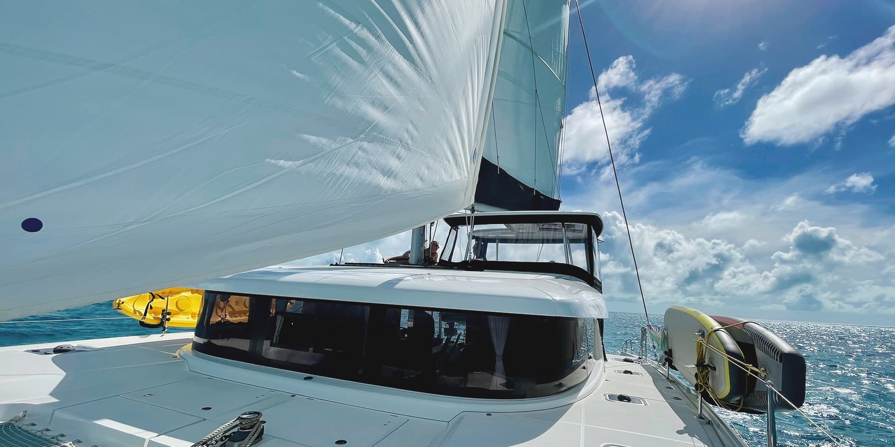 Sailing catamaran under full sail on turquoise sea, deck view