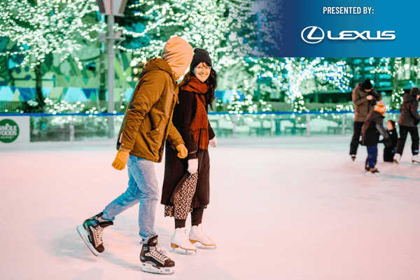 Couple ice skating at illuminated Campus Martius Park rink