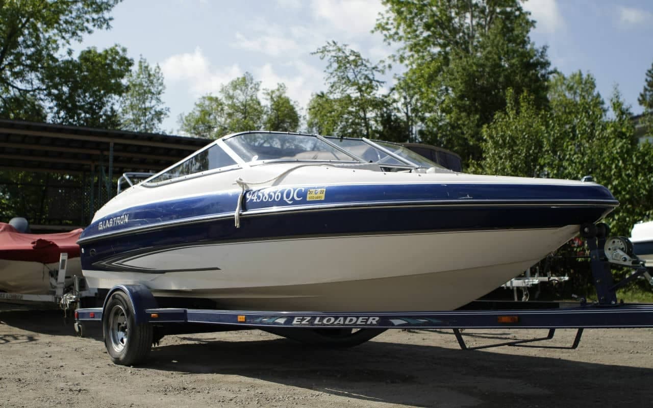 Blue and white bowrider boat parked on trailer at marina lot
