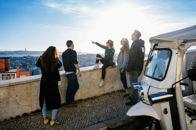 Group enjoying coastal city viewpoint and tuk-tuk tour in Lisbon