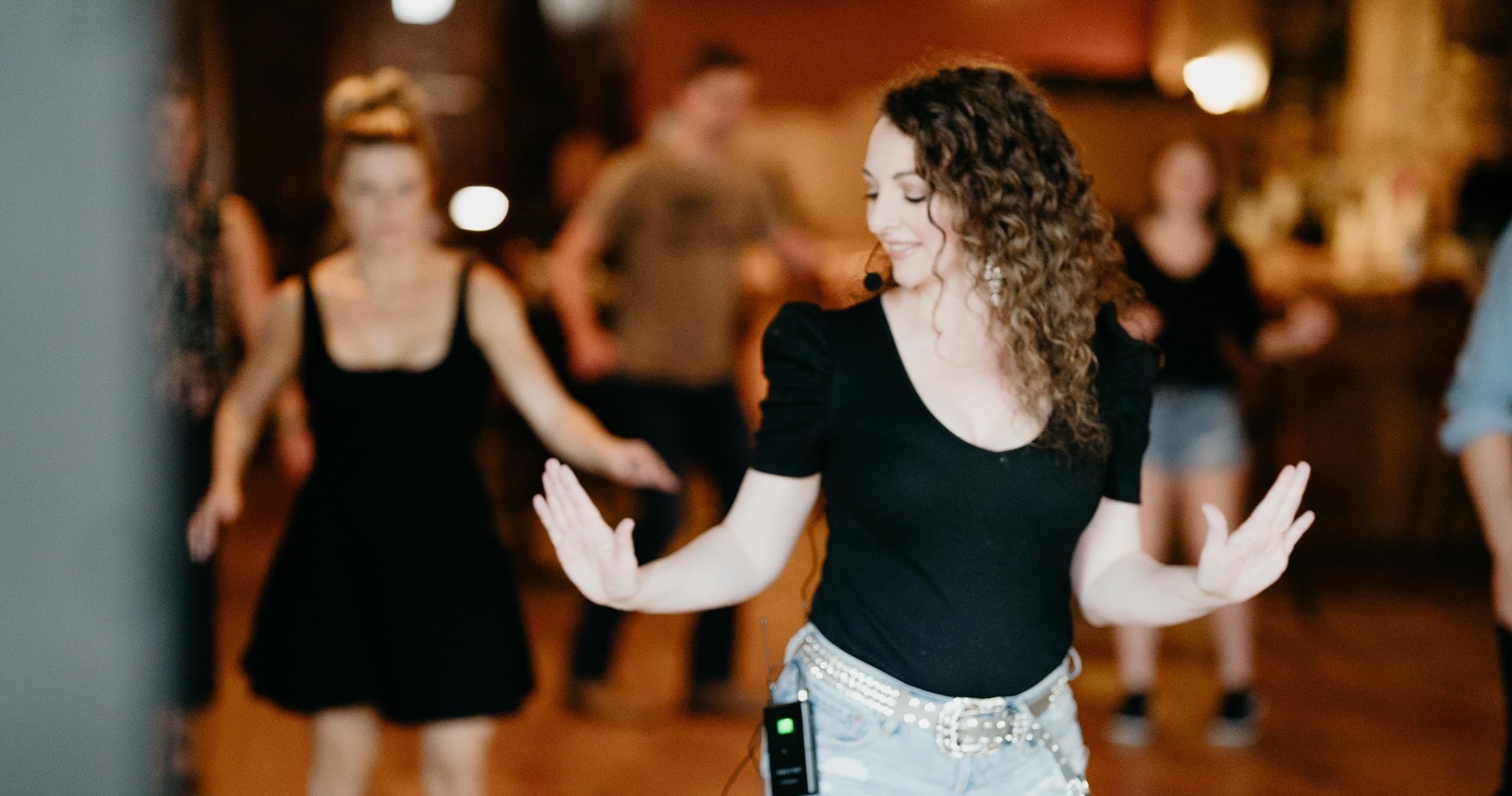 Country line dancers practicing spins in indoor wooden dance hall