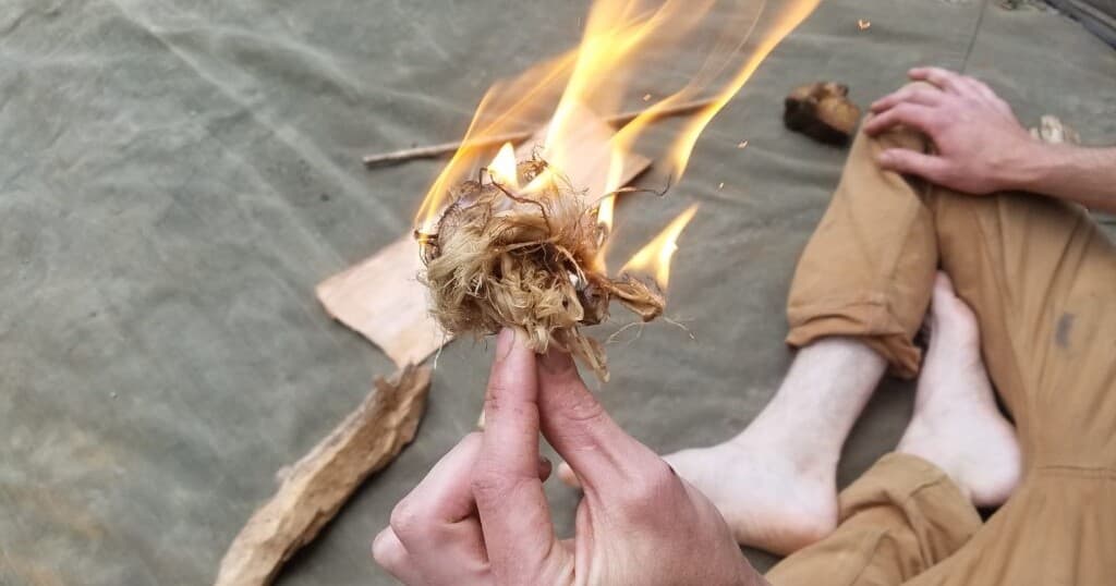 Hands making a tinder bundle fire during outdoor bushcraft
