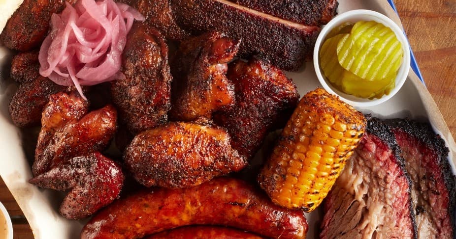 Smoked barbecue platter on wooden board, communal BBQ feast