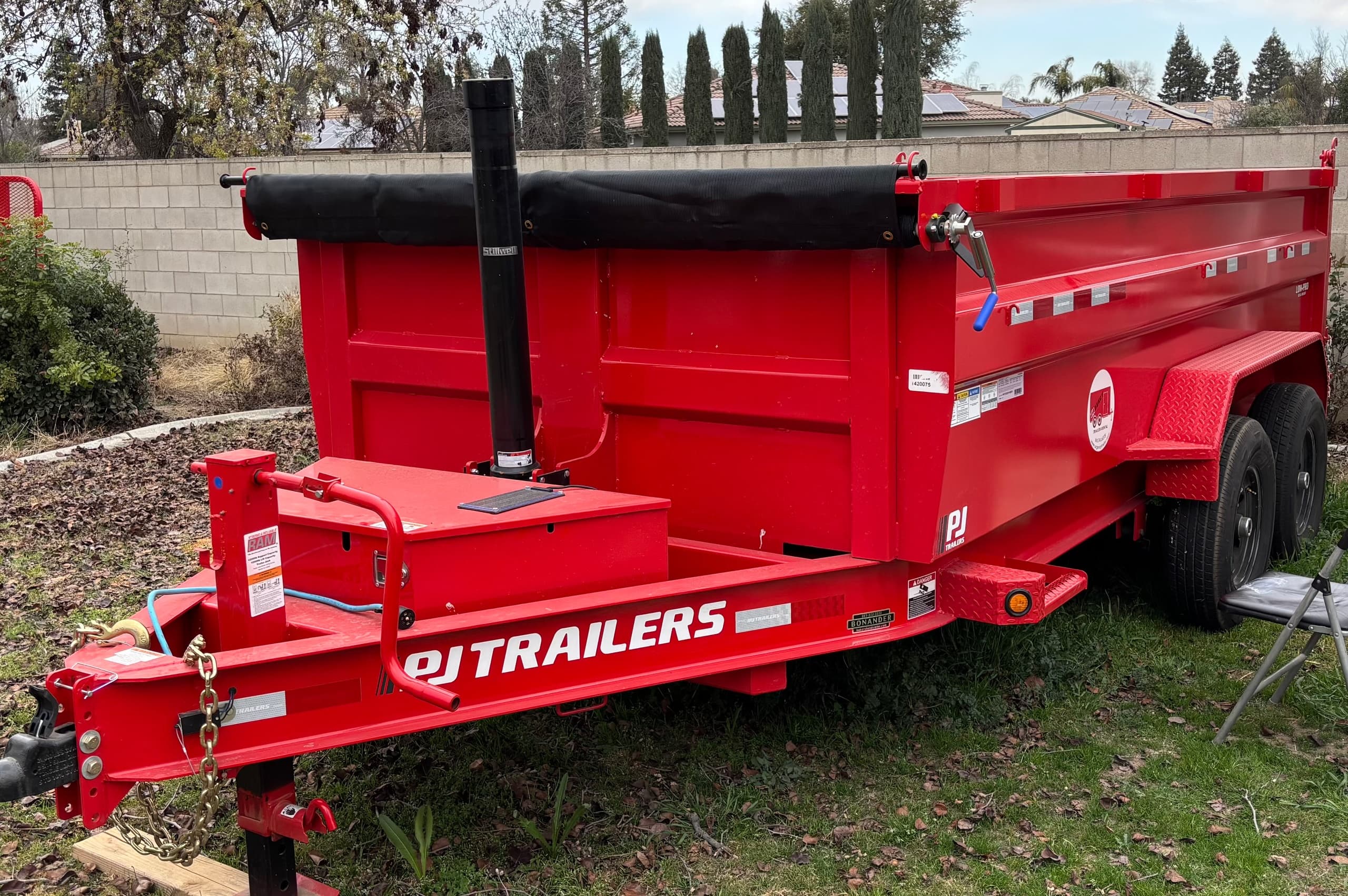 Red dump trailer parked in yard ready for hauling debris outdoors