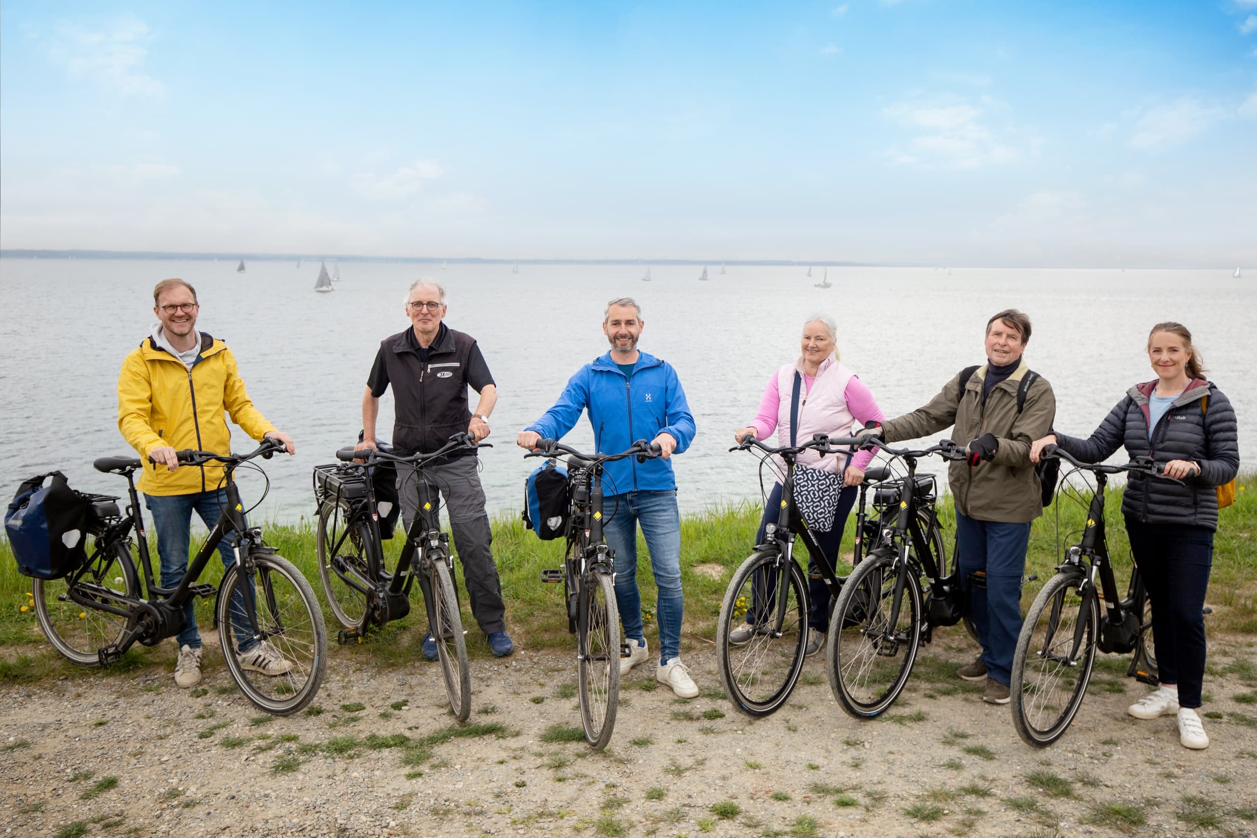 Group bicycle tour by the sea with riders posing on shore