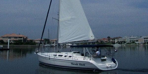 Single sailboat under white sails in calm marina waters