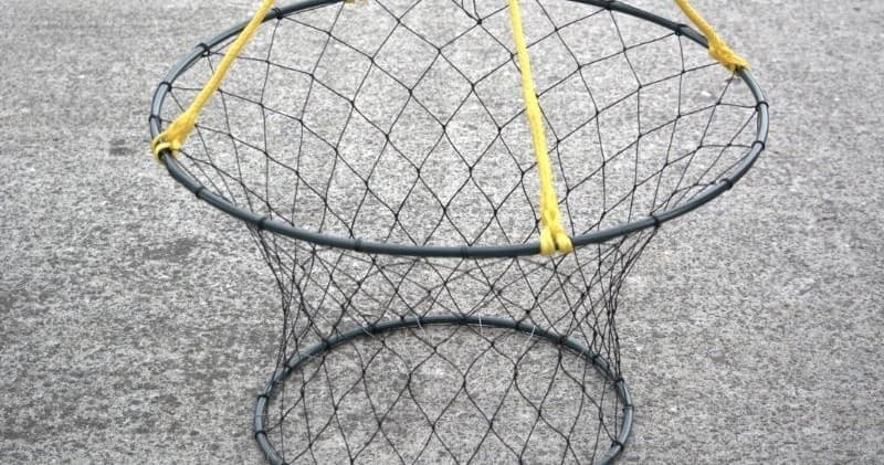 Collapsible crab pot set on dock surface ready for crabbing