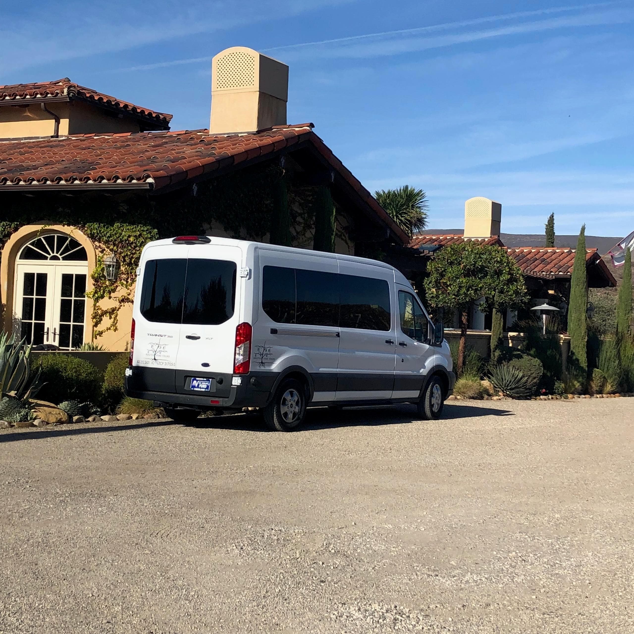 Tour van parked outside rustic winery estate under blue sky