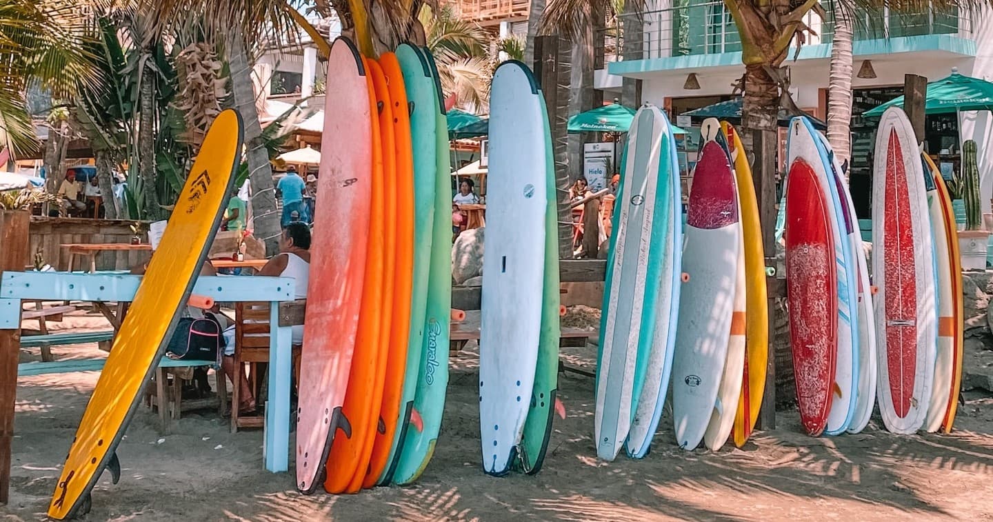 Assorted surfboards leaned against rack on sunlit beach