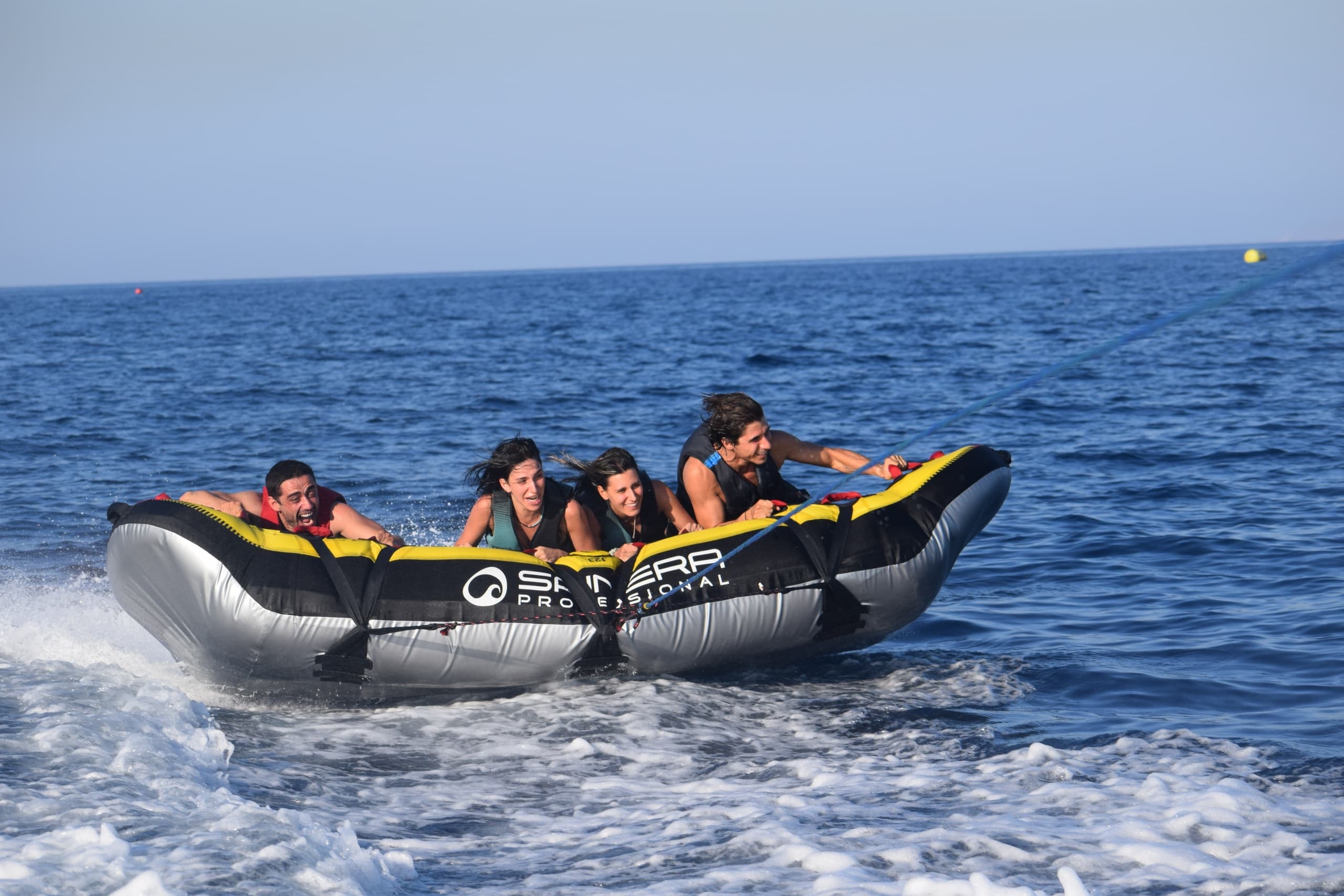 Group on inflatable banana boat towed across deep blue ocean