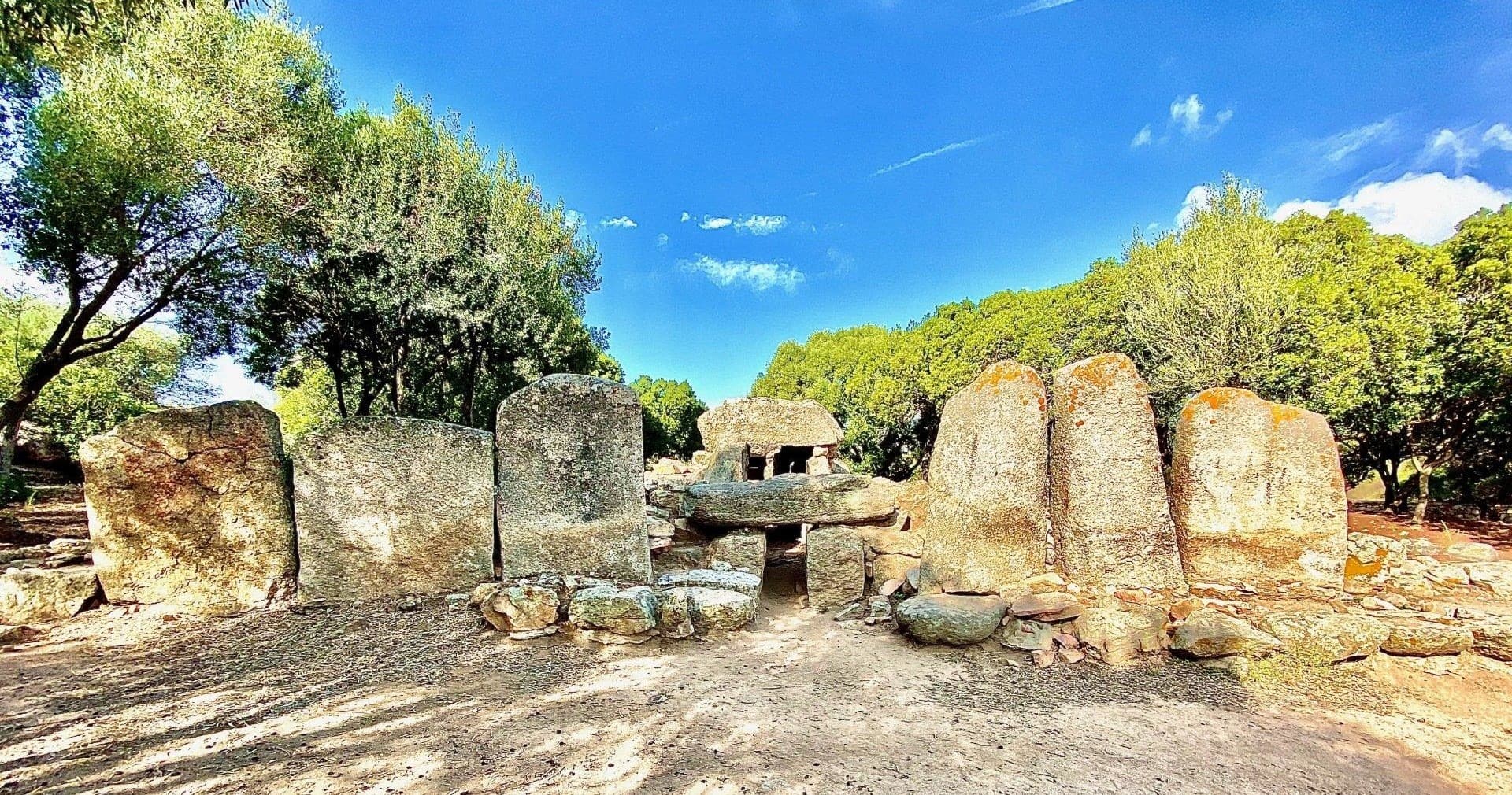 Ancient megalithic stone tombs in sunlit Mediterranean scrub