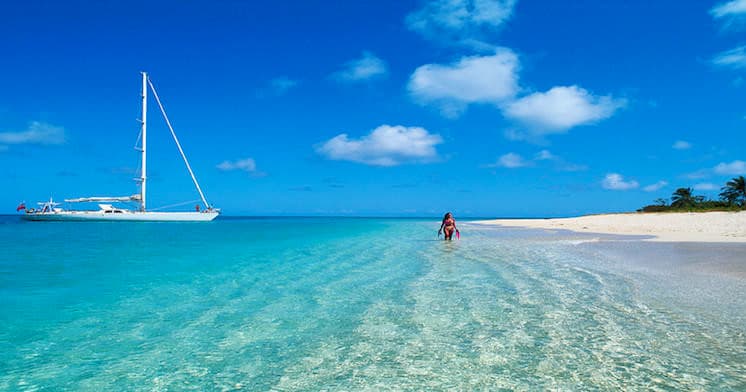 Sailboat anchored by turquoise Caribbean beach, shallow water