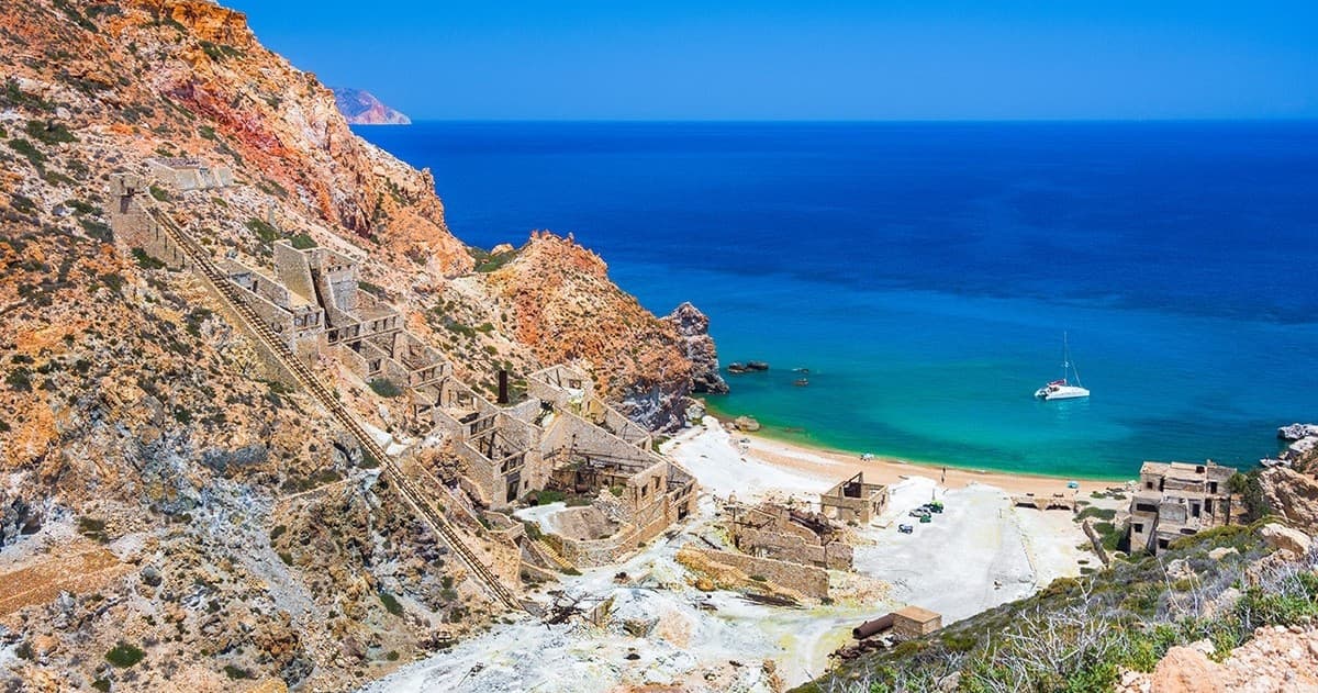 Rocky coastline with turquoise sea and anchored sailboat view